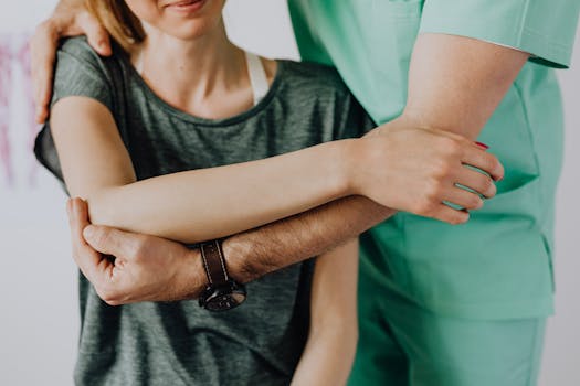 Leistungen Crop anonymous chiropractor in uniform and wristwatch examining shoulder of smiling faceless woman in casual clothes in doctor office in clinic