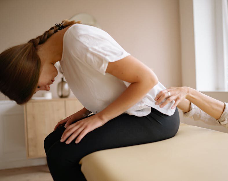 Leistungen A therapist stretches a patient's back during a physical therapy session indoors.